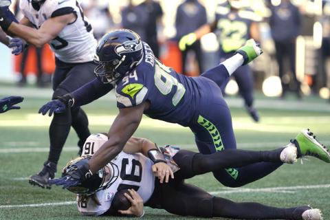 Seattle Seahawks' Rasheem Green tumbles across Jacksonville Jaguars quarterback Trevor Lawrence after Lawrence kept the ball on a carry during Sunday’s game Sunday in Seattle. (TED S. WARREN/Associated Press)