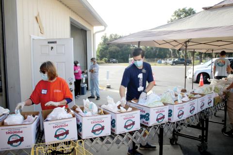 Volunteers put food into Thanksgiving baskets Thursday morning at Catholic Charities. More than 90 volunteers helped distribute 565 Thanksgiving baskets to local families. (TONY BRITT/Lake City Reporter)