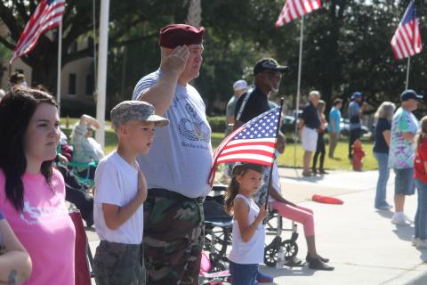 Liam Ambrose (from left), 10, U.S. Army veteran Harrison Ambrose and Bailee Ambrose, 7, stand as the Columbia High School band plays the National Anthem during Thursday’s Veterans Day parade in Lake City. (TONY BRITT/Lake City Reporter)