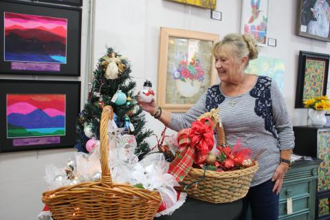 Cindy Sleezer checks out a snowman ornament at the Gateway Art Gallery. (TONY BRITT/Lake City Reporter)