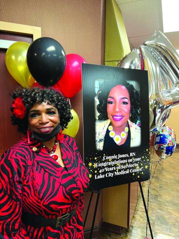 Connie Jones smiles next to a sign honoring her 40 years working at Lake City Medical Center. (COURTESY)