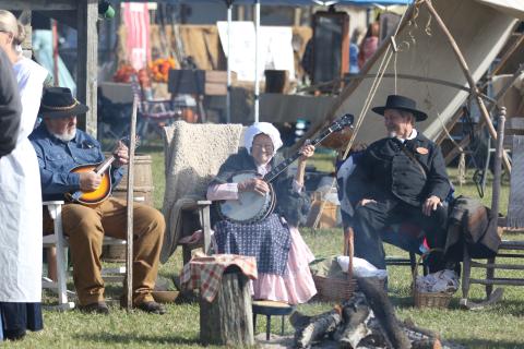Margie Markham (middle) strums on her banjo alongside Fred Parnell (left) and Graycyn Markham (right) during Saturday’s Founder’s Day festival. (MORGAN MCMULLEN/Lake City Reporter)