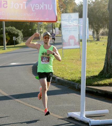 Peter Laughlin crosses the finish line to win the inaugural Turkey Trot 5K at Wilson Park in downtown Lake City on Thanksgiving morning. (JAMIE WACHTER/Lake City Reporter)