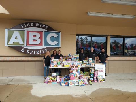 The Lake City ABC Fine Wine & Spirits employees Evelyn Alexander (from left), Sharde Chairs, Teresa Sullivan, Annettee Baker, Tom Stauffer and Chris Moll stand near the toys they purchased for the Toys For Tots program after a recent toy drive. (COURTESY)