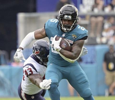 Jacksonville Jaguars running back James Robinson, right, tries to get past Houston Texans middle linebacker Neville Hewitt during Sunday’s game in Jacksonville. (PHELAN M. EBENHACK/Associated Press)