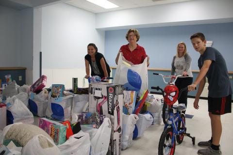 Christmas Dream Machine volunteers Jennifer Munroe (from left), Janet Stanford, Angela Towns and Walker Munroe, organize toys for the Christmas Dream Machine Toy Distribution which took place Sunday afternoon. (TONY BRITT/Lake City Reporter)