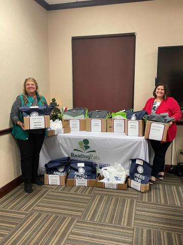 Donna MacRae (left) and Jennifer Lee, with United Way of Suwannee Valley Women United, hold and show boxes of books that go to local elementary school kindergartners during the Christmas break to help improve their literacy skills. (COURTESY)
