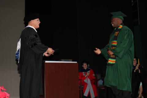 A Florida Gateway College graduate walks across the stage Friday during a commencement ceremony to receive his degree from Brian Dopson, the college’s vice president of academic affairs. FGC hosted the first two of four graduation ceremonies Friday, the other two are scheduled for Monday. (TONY BRITT/Lake City Reporter)