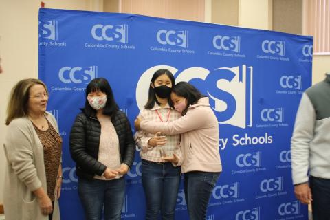 Cindy Kim (center) gets a hug from her sister, Arienna, alongside their mother, Ae-yun Shin. (TONY BRITT/Lake City Reporter)