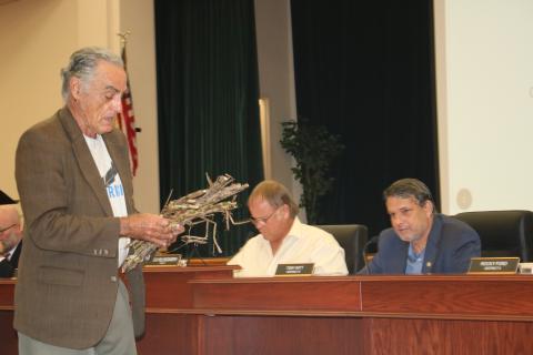 Tom Cunilio (from left), representing the Center of Sustainable Agroforestry, provides Columbia County commissioners Robby Hollingsworth and Toby Witt, with samples during Thursday’s night’s commission meeting as he requested funding for a a field day showcasing energy crops. (TONY BRITT/Lake City Reporter)