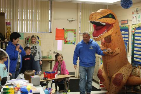 Roger Little (right), Eastside Elementary School principal, holds the hand of ‘Trixie The T-Rex’ as he introduces her to Terry Brewer’s kindergarten class. (TONY BRITT/Lake City Reporter)