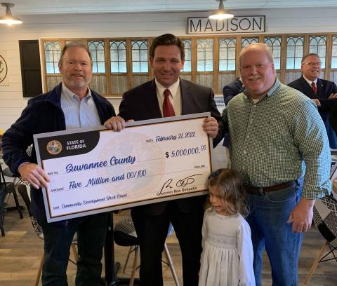 Gov. Ron DeSantis and his daughter Madison present a check to Suwannee County Administrator Randy Harris (left) and Shannon Roberts on Monday at an appearance in Madison. (COURTESY)