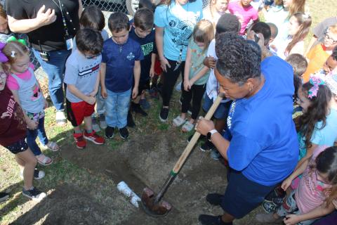 Scharlotte Stewart, Eastside Elementary School lead custodian, uses a shovel to cover a time capsule at the base of the school sign on Tuesday, 2/22/22. The capsule, which was placed by first graders, is scheduled to be open in 11 years, on 3/3/33, when the students are high school seniors. (TONY BRITT/Lake City Reporter)