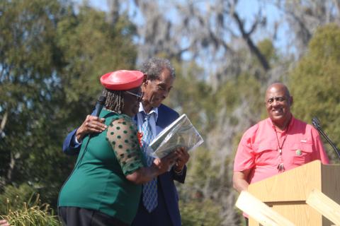 Lelia Williams (from left) is hugged by Rev. Herman Grant as Philip Mobley looks on during the Richardson Historic Marker celebration. Grant presented Williams with a plaque of appreciation for her support in helping get the historic marker for Richardson High School. (TONY BRITT/Lake City Reporter)
