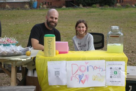 Corey Burk (left) and Lexi Mccardle sit behind Lexi’s lemonade stand Thursday afternoon. (MORGAN MCMULLEN/Lake City Reporter)