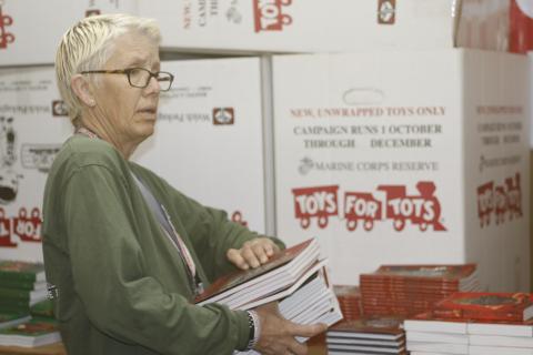 Inga Dwyer, the Toys for Tots coordinator for Columbia and Suwannee counties, helps load a stack of books Thursday for the Lake City Christian Academy. Dwyer used leftover funds to provide books for local schools during Literacy Month. (JAMIE WACHTER/Lake City Reporter)