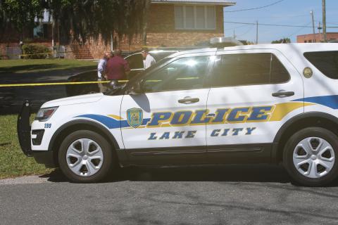 LCPD detectives huddle up in a parking lot near Lake DeSoto Monday morning following a report of two dead bodies in a vehicle. (JAMIE WACHTER/Lake City Reporter)
