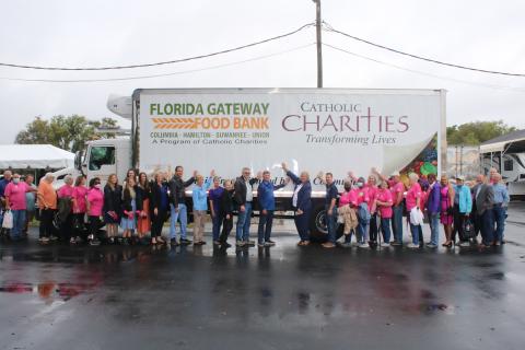 Members and volunteers with Catholic Charities put their hands on a refrigerated food truck bought by the organization in February. (TONY BRITT/Lake City Reporter)