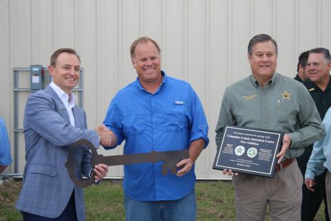 Jay Smith, Ajax Building Company vice president (from left), accepts a ceremonial key from Robby Hollingsworth, Columbia County Commission chairman, as Sheriff Mark Hunter holds a plaque noting the completion of the Columbia County Detention Facility addition. (TONY BRITT/Lake City Reporter)