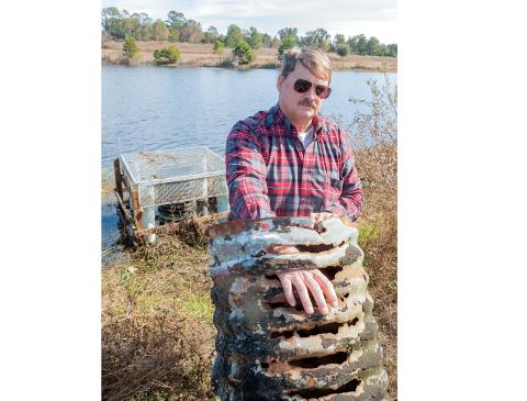 In this 2014 file photo, Jeffrey Hill poses with the rusty pipe at the heart of his dispute. (FILE)