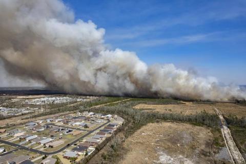 A fast-moving wildfire looms over homes outside of Panama City on Friday. More than 200 firefighters and emergency workers from throughout the Florida Panhandle worked overnight into Saturday, to strengthen containment lines and protect homes. (MIKE FENDER/News Herald/AP)