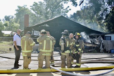 Columbia County Assistant Fire Chief Lance Hill (left) talks with firefighters after they extinguished the flames in a house fire Tuesday morning on SE Montrose Avenue. (TODD WILSON)