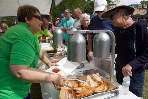 A volunteer serves up some fried catfish during a previous year’s Suwannee River Catfish Festival in Branford. (Suwannee Democrat File)