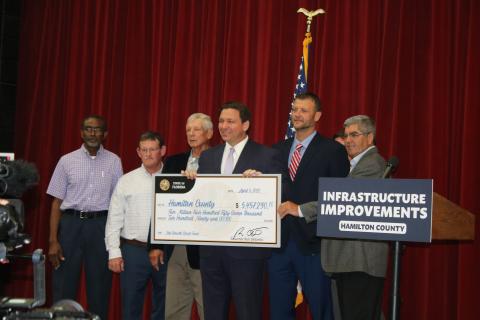 Gov. Ron DeSantis presents a check for $5.4 million for infrastructure improvements to Hamilton County Commissioners Robert Brown (from left), Richie McCoy, Jimmy Murphy, Josh Smith and Randy Ogburn during a press conference Tuesday in Jasper. (TONY BRITT/Lake City Reporter)