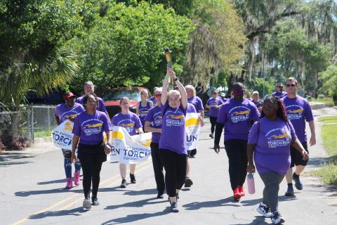 A participant in Tuesday’s Law Enforcement Torch Run for Special Olympics hoists the torch up above her head. (TONY BRITT/Lake City Reporter)