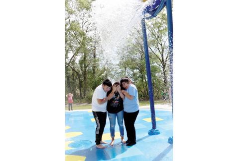 A group of children brace for the water to fall on them from a dumping bucket at the new splash pad at the First Federal Sportsplex in Live Oak. The splash pad opened last week. (PAUL BUCHANAN/Special to the Reporter)