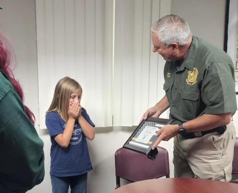 Olivia Cauley, 9, receives an ‘official superhero’ certificate from Suwannee County Sheriff Sam St. John on Tuesday for her actions on May 14 to assist her mother, Stephanie, following a medical emergency. (COURTESY)