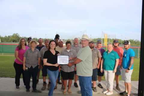 Columbia County Tourist Development Council Executive Director Paula Vann presents Clint Pittman, the county’s Landscapes and Parks director, a certificate Tuesday morning at Southside Sports Complex for helping advance tourism in the county as they are joined by TDC and park staff. (TONY BRITT/Lake City Reporter)