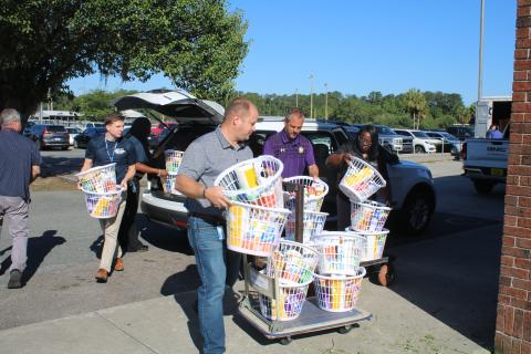 Trent Linn (from left), Lake City Correctional Facility Core Civic business manager, Daniel Taylor, Columbia High School principal Trey Hosford and Sonical Mitchell, local “baskets of love” onto trailers Thursday morning at Columbia High School. (TONY BRITT/Lake City Reporter)