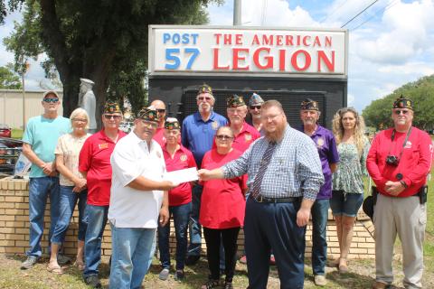 Rick Cabrera, American Legion Post 57 commander (front row, from left) gives Chris Esing a contribution to aid in the purchase of a War on Terror memorial monument on Friday afternoon. Other Post 57 members in attendance were: Jim Taylor (middle row, from left), Rustyann Brown, Laura Cabrera, Bill Huggins, Jim Reherman and Thomas Wilcutts; Steve Cox (back row, from left), Debbie Cox, Michael Ziegler, Thomas Johnson, Mitchell Cooper and Dianna Cooper. (TONY BRITT/Lake City Reporter)