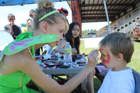 Faith Ingram (left), of the Columbia High School drama club, adds the finishing touches to Xavier Boutwell’s face paint at the Kiwanis Kids Day. (TONY BRITT/Lake City Reporter)
