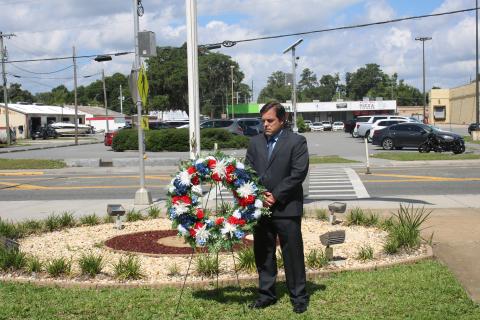 Chad Adams, the associate director for operations at the Lake City VA Medical Center, solemnly reflects after placing a wreath outside the facility Wednesday. (TONY BRITT/Lake City Reporter)