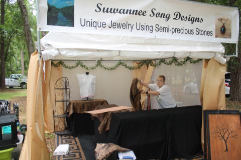 Lynne Hutchins, of Live Oak, sets up her Suwannee Song Designs booth at Stephen Foster Park for this weekend’s 70th annual Florida Folk Festival. (TONY BRITT/Lake City Reporter)