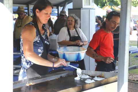 Volunteer Jennifer Petit puts fresh blueberry pancake batter on the griddle during the blueberry pancake breakfast at last year’s Wellborn Blueberry Festival. (FILE)