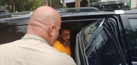 Thomas Walker (right) is placed in the back of a Live Oak Police Department vehicle after he was arrested Friday. (COURTESY)