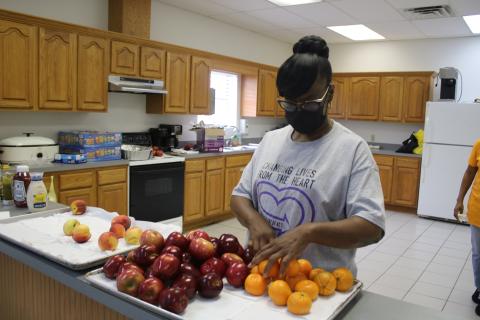 Essie Akins, a Straight From the Heart of North Florida committee member, arranges fruit during the organization’s inaugural community event on Saturday at the Fort White Community Center. (TONY BRITT/Lake City Reporter)