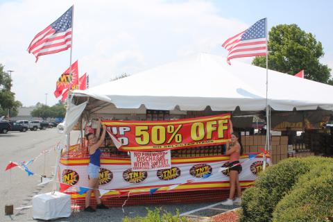 Kenzie Dungan (left), Columbia FFA senior president and her sister, Kaylan Dungan, Columbia FFA junior president, set up a banner outside the FFA fireworks stand Friday afternoon. (TONY BRITT/Lake City Reporter)