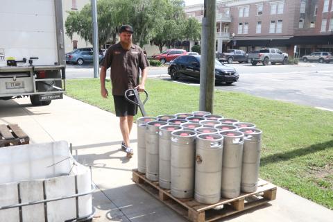 Jonny Frazier walks a pallet of 19 kegs of beer toward a Savannah Distributing truck near the loading ramp at Halpatter Brewing Company on Monday. (MORGAN MCMULLEN/Lake City Reporter)