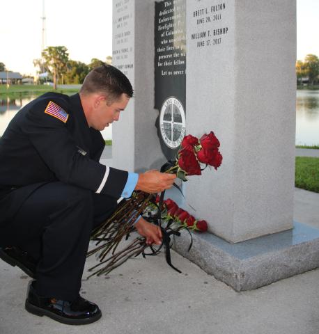 Austin Thomas, a Lake City Fire Department driver/engineer, lays roses on the Columbia County Public Safety Memorial on Tuesday in honor of fallen Columbia County public safety workers. (TONY BRITT/Lake City Reporter)