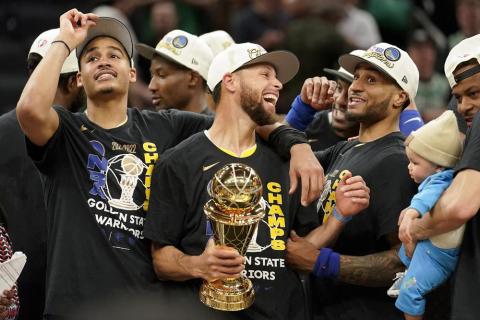 Golden State Warriors guard Stephen Curry, center, celebrates with teammates as he holds the Bill Russell Trophy for Most Valuable Player after the Warriors beat the Boston Celtics in Game 6 of the NBA Finals on Thursday to win their fourth title in eight years. (STEVEN SENNE/Associated Press)