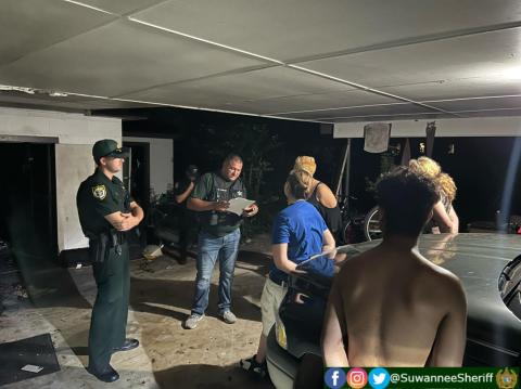 Wayne Kelly, an investigator with the Suwannee County Sheriff’s Office, talks with suspects Jacqueline White, Bridget Parks and Travis Eshleman following a drug bust Thursday night in Live Oak. (COURTESY SUWANNEE COUNTY SHERIFF’S OFFICE)