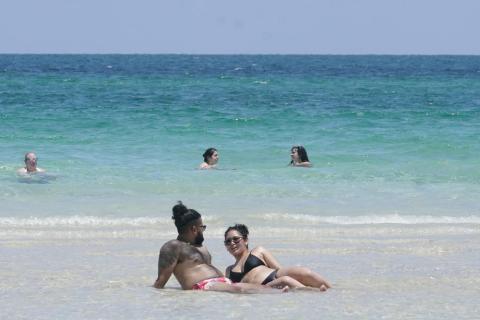 A couple sun bathes on a sand bar July 13 in Miami Beach. (MARTA LAVANDIER/Associated Press)