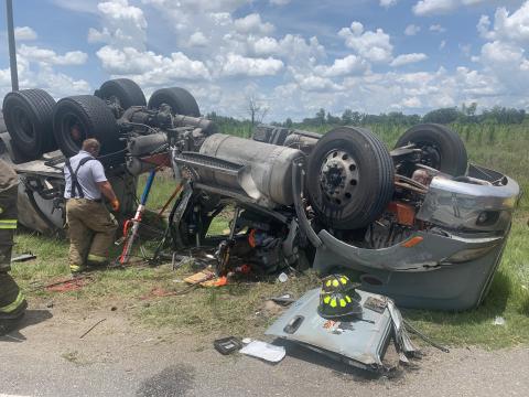 A member of Columbia County Fire Rescue looks at an overturned semi along U.S. Highway 27 in Suwannee County on Wednesday afternoon in which the driver was trapped and suffered serious injuries. (COURTESY SUWANNEE COUNTY FIRE RESCUE)