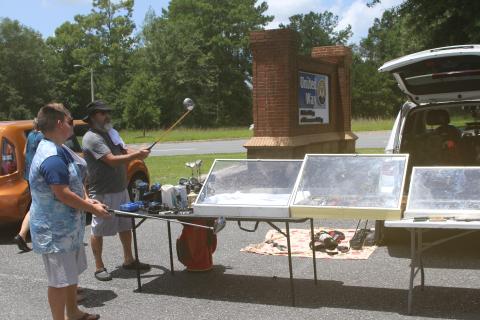 Prospective buyers take a closer look at a pair of golf clubs at Friday’s United Way of Suwannee Valley community yard sale. (TONY BRITT/Lake City Reporter)