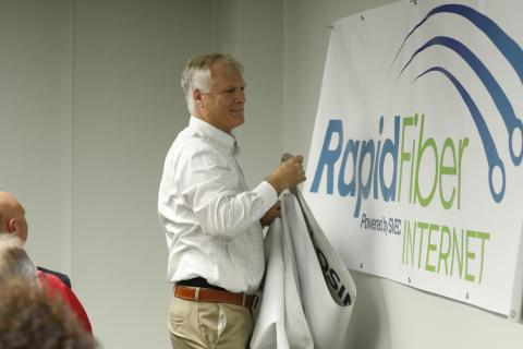 SVEC Communications Director Jon Little unveils the new logo for Rapid Fiber Internet on Tuesday. (JAMIE WACHTER/Lake City Reporter)