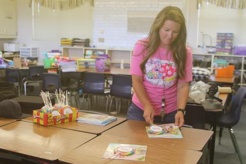 Amber Thomas, an Eastside Elementary School second grade teacher, sets a lollipop and book on desks Wednesday. (TONY BRITT/Lake City Reporter)